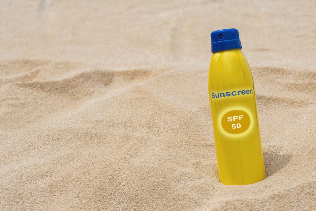 Image of sunscreen bottle in the sand for products with benzene blog post