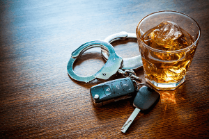 Stock image of liquor glass, handcuffs and car keys 