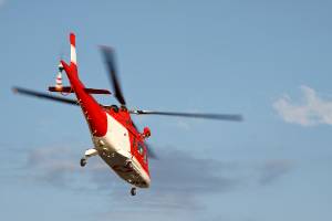 white and red medical helicopter in air