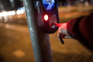 Img of pedestrian pressing a crosswalk button at night