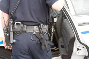 police officer holding open rear door of cruiser