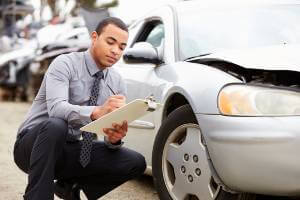 insurance adjuster taking notes about damaged car